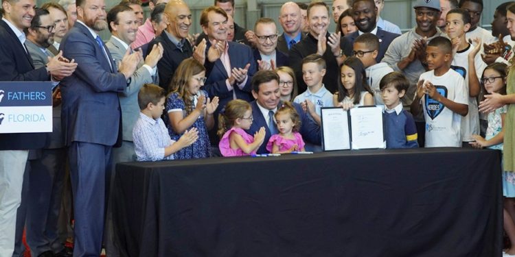 Junto a sus hijas, el gobernador Ron DeSantis firmó la ley para incentivar la paternidad. (Twitter)